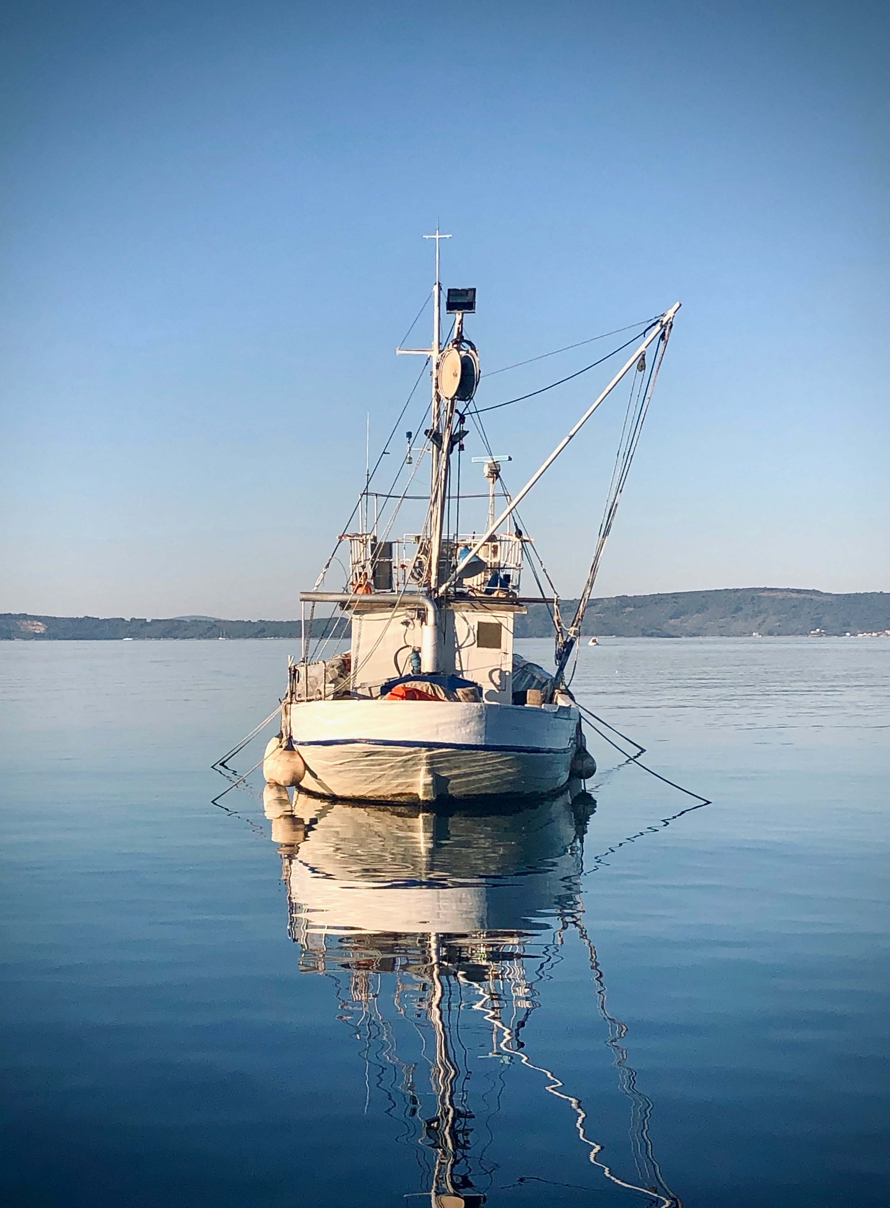 White fishing boat in water with clear blue sky